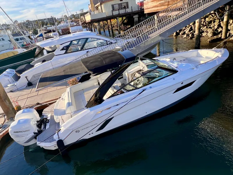 Slide: The Image of 2020 Cruisers Yachts 338OB docked in marina, featuring sleek design and twin Mercury engines. - 2