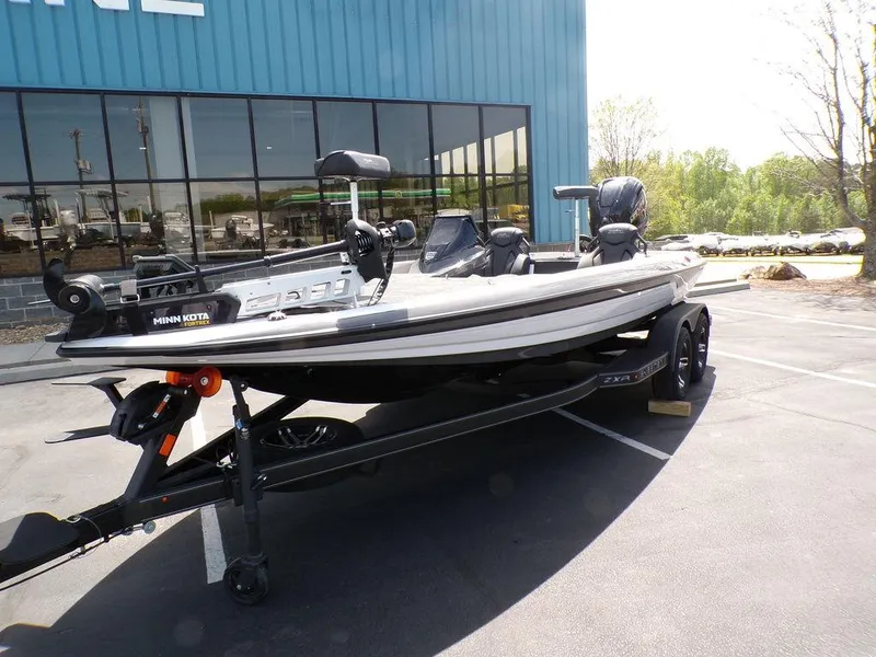 Slide: The Image of 2025 Skeeter ZXR19 fishing boat on trailer, parked outside a blue building. - 23