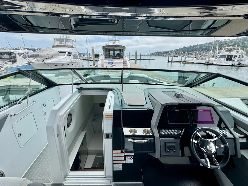 Slide: The Image of 2023 Cruisers Yachts 34 GLS I/O helm with modern controls, docked at marina. - 24