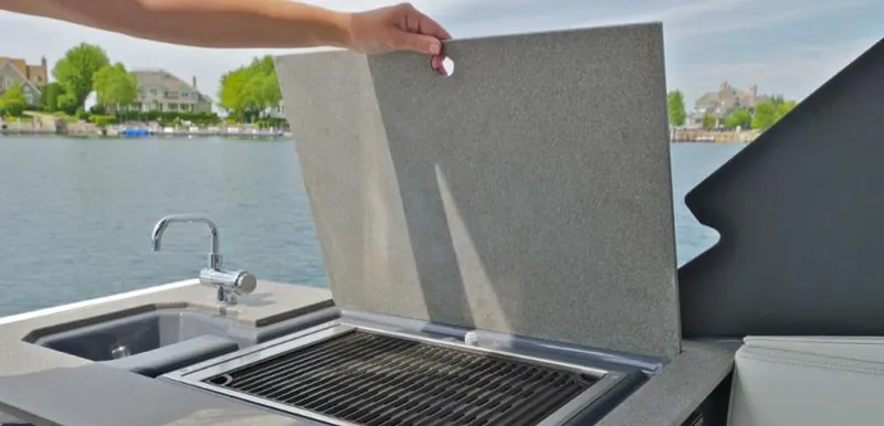Slide: The Image of 2023 Cruisers Yachts 34 GLS I/O outdoor kitchen with grill and sink by the water. - 17