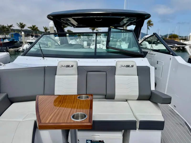 Slide: The Image of 2023 Cruisers Yachts 34 GLS I/O boat interior with seating and table, docked at marina. - 36
