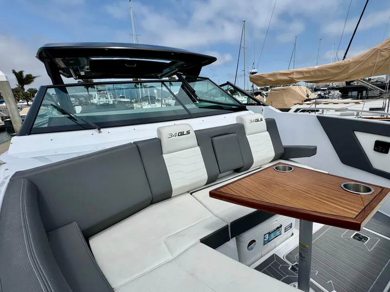 Slide: The Image of 2023 Cruisers Yachts 34 GLS I/O with sleek seating and wooden table, docked at marina. - 38