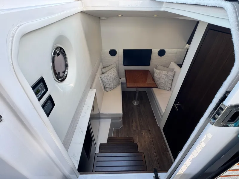 Slide: The Image of 2023 Cruisers Yachts 34 GLS I/O cabin interior with seating, table, and porthole. - 44
