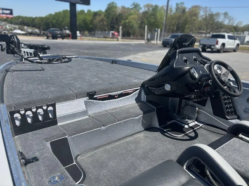 Slide: The Image of 2025 Phoenix 721 ZXL boat interior with steering wheel and spacious deck, parked outdoors. - 12