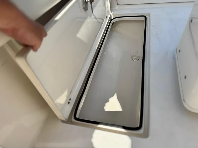 Slide: The Image of 2017 Cobia 237 Center Console storage compartment, open lid, white interior. - 28