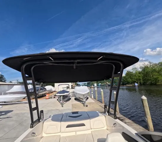 Slide: The Image of 2016 Chaparral 19 H2O Sport boat docked by a serene waterfront under a clear blue sky. - 15