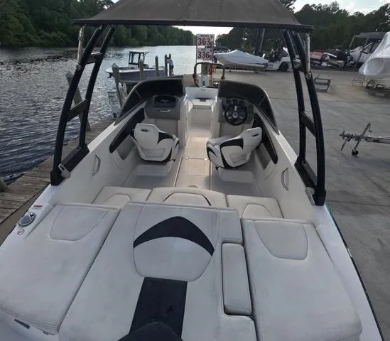 Slide: The Image of 2016 Chaparral 19 H2O Sport boat interior with seating and steering wheel, docked by a river. - 4