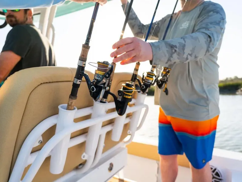 Slide: The Image of Men organizing fishing rods on a 2025 Sportsman Masters 227 boat. - 19