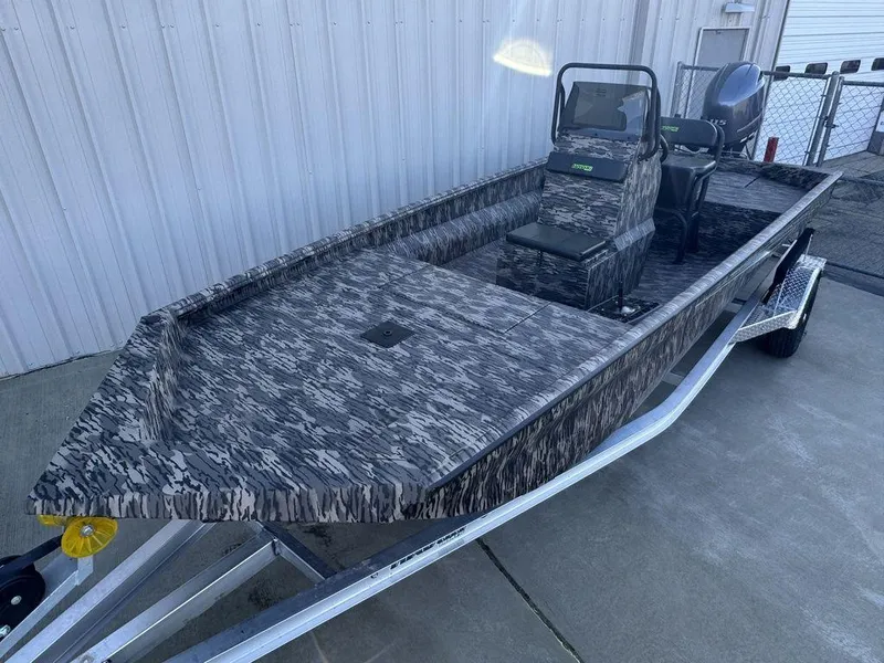 Slide: The Image of Camouflage-patterned 2025 Havoc 1965 UCC boat on trailer, parked near a metal building. - 4