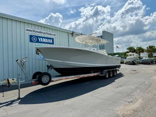 Slide: The Image of 2017 Regulator 31 boat on trailer outside Yamaha dealership under cloudy sky. - 1
