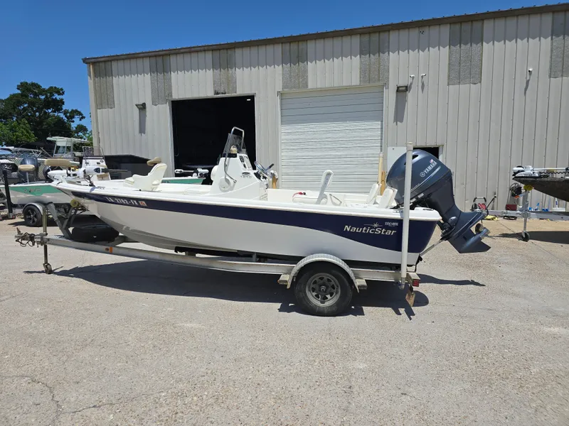 Slide: The Image of 2010 NauticStar 1810 Nautic Bay boat on trailer, parked outside a warehouse. - 2