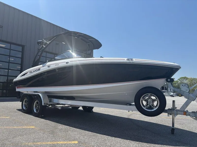 Slide: The Image of 2024 Tahoe 210 S boat on trailer, parked outdoors under clear blue sky. - 7