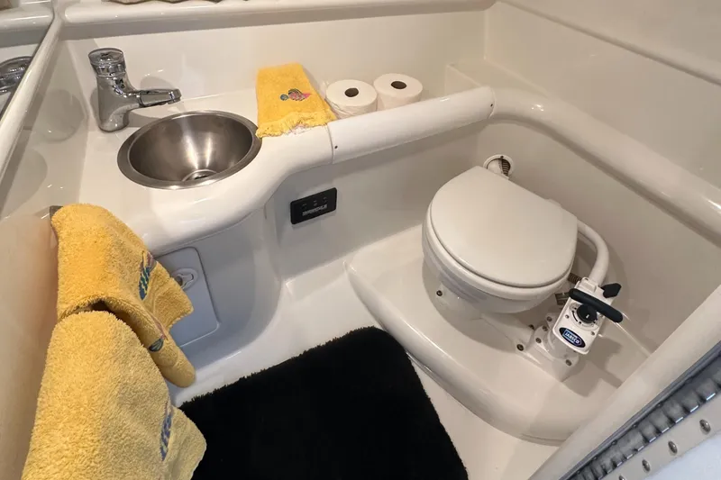 Slide: The Image of 1998 Formula 330 SunSport boat bathroom with sink, toilet, and yellow towels. - 24