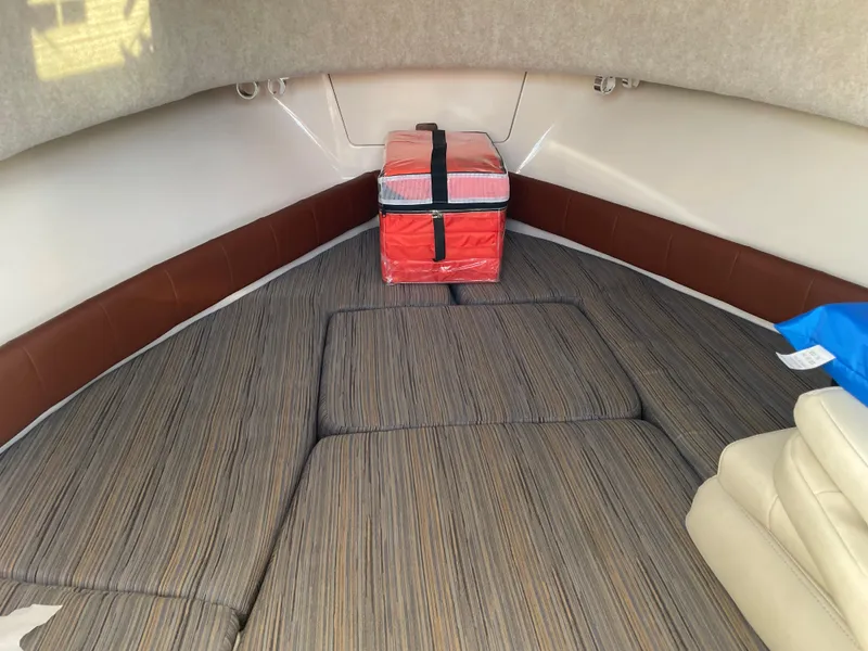 Slide: The Image of 2015 Grady-White Seafarer 226 cabin interior with striped cushions and a red storage box. - 15