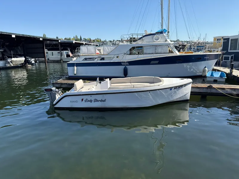 Slide: The Image of 2022 Rand Picnic boat docked at marina, calm water, clear sky. - 10