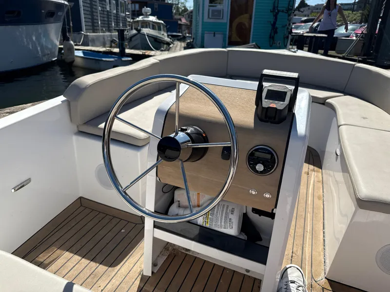 Slide: The Image of Steering wheel of a 2022 Rand Picnic boat with wooden dashboard and seating. - 2