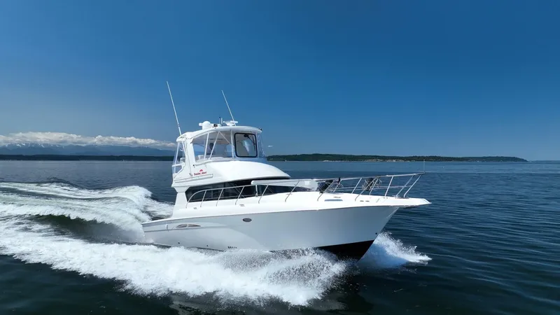 Slide: The Image of 2006 Silverton 42 Convertible yacht cruising on open water under clear blue sky. - 0