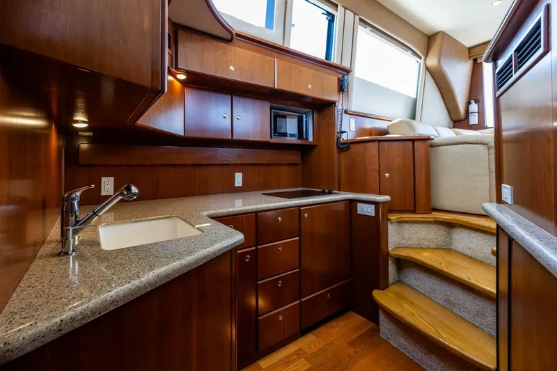 Slide: The Image of 2006 Silverton 42 Convertible yacht interior with modern kitchen and wooden cabinetry. - 17