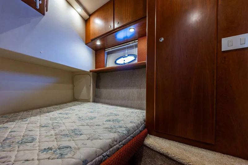Slide: The Image of 2006 Silverton 42 Convertible cabin interior with bed, wooden cabinets, and porthole window. - 23