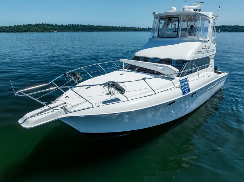 Slide: The Image of 2006 Silverton 42 Convertible yacht on calm water, showcasing sleek design and spacious deck. - 42