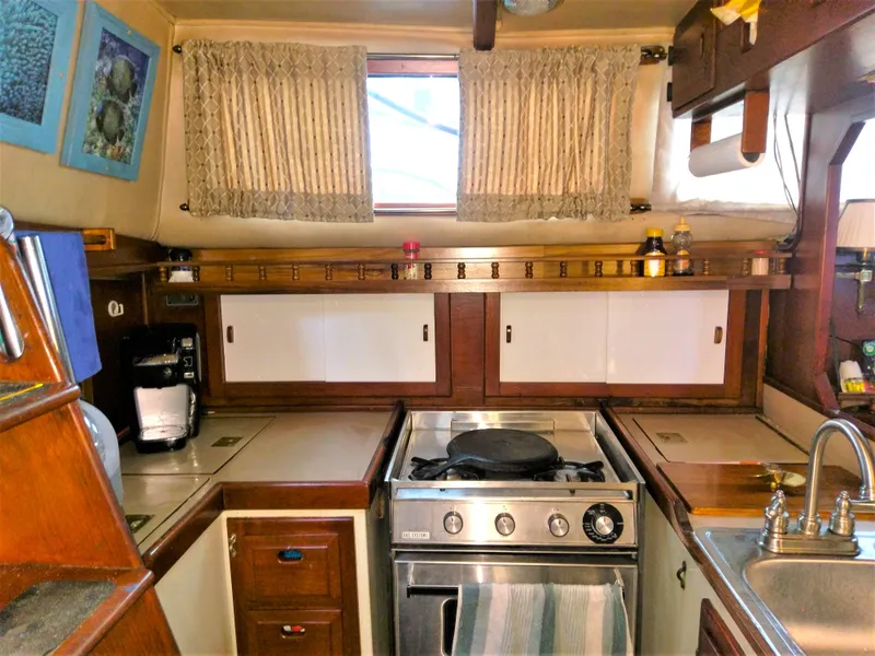Slide: The Image of 1975 Downeast Ketch kitchen with stove, sink, and wooden cabinetry. - 25