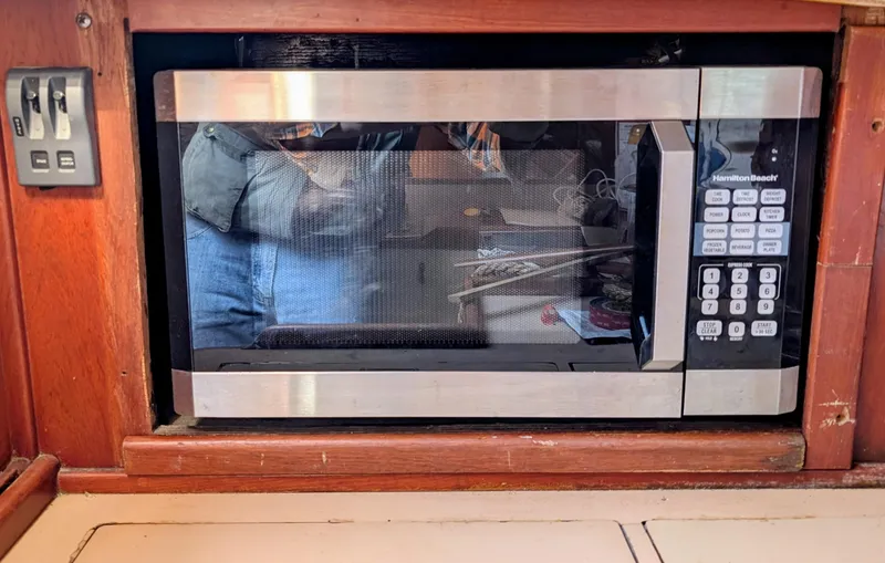 Slide: The Image of Microwave installed in a 1975 Downeast Ketch, surrounded by wooden cabinetry. - 27