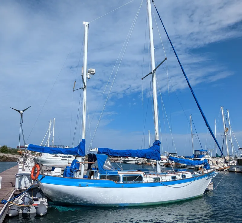 Slide: The Image of 1975 Downeast Ketch sailboat docked at marina under blue sky. - 3