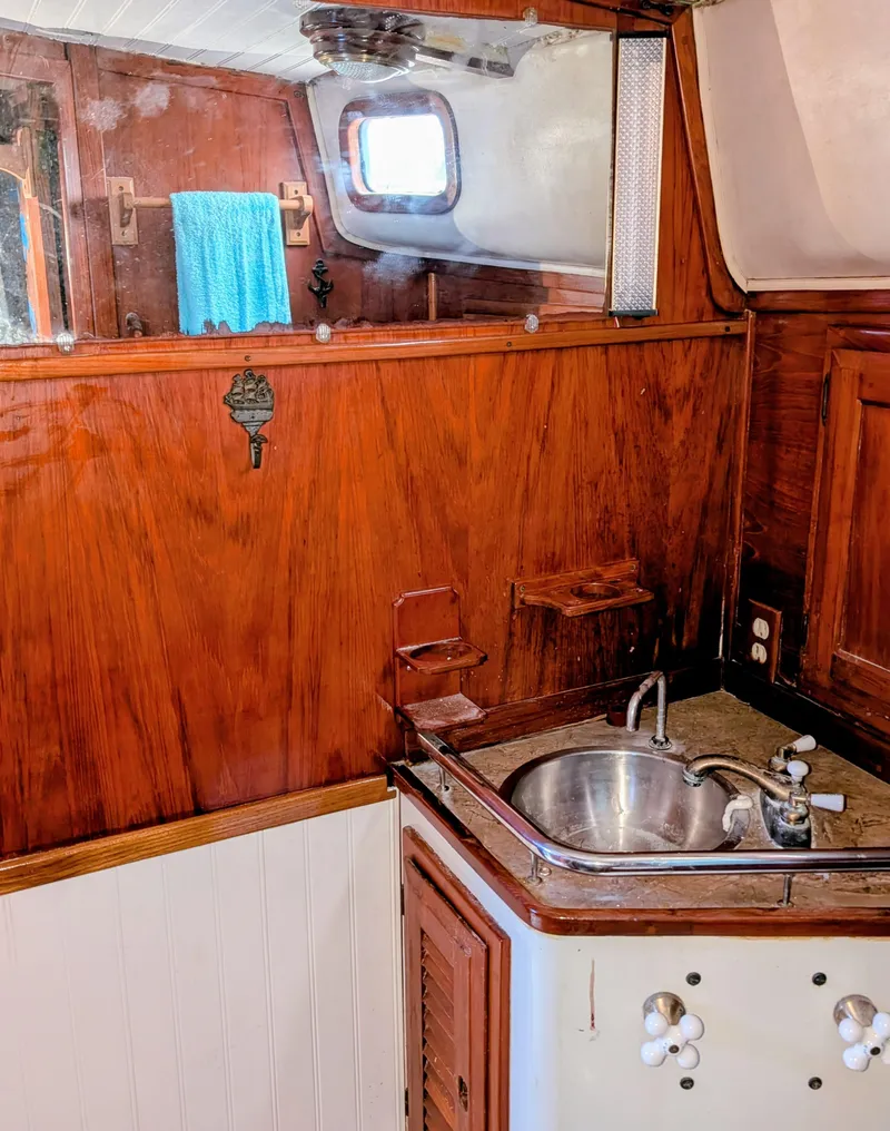 Slide: The Image of 1975 Downeast Ketch interior with wooden cabinetry and compact sink area. - 32