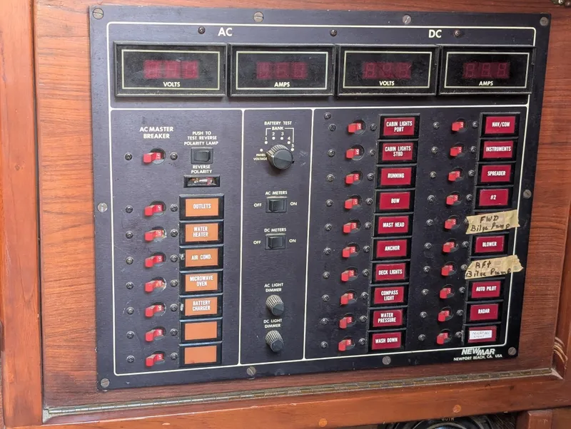 Slide: The Image of Electrical control panel on a 1975 Downeast Ketch boat, featuring AC and DC switches and meters. - 34