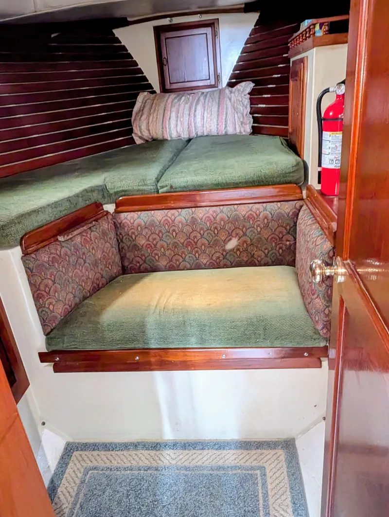 Slide: The Image of 1975 Downeast Ketch interior with cozy seating, wooden accents, and a fire extinguisher. - 36