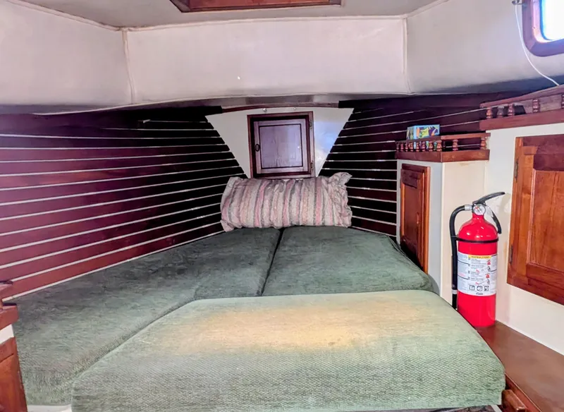 Slide: The Image of 1975 Downeast Ketch cabin interior with bed, wooden paneling, and fire extinguisher. - 37