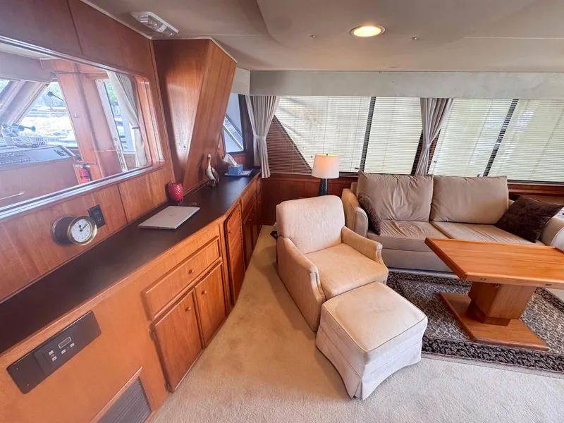 Slide: The Image of 1988 Chris-Craft 501 Motor Yacht interior with cozy seating, wooden cabinetry, and large windows. - 16