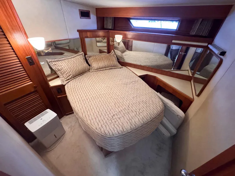 Slide: The Image of 1988 Chris-Craft 501 Motor Yacht bedroom with cozy bed, wooden accents, and ambient lighting. - 24