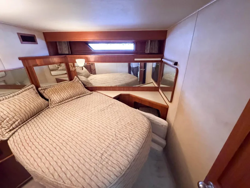 Slide: The Image of 1988 Chris-Craft 501 Motor Yacht bedroom with cozy bed, wood accents, and mirrored walls. - 25