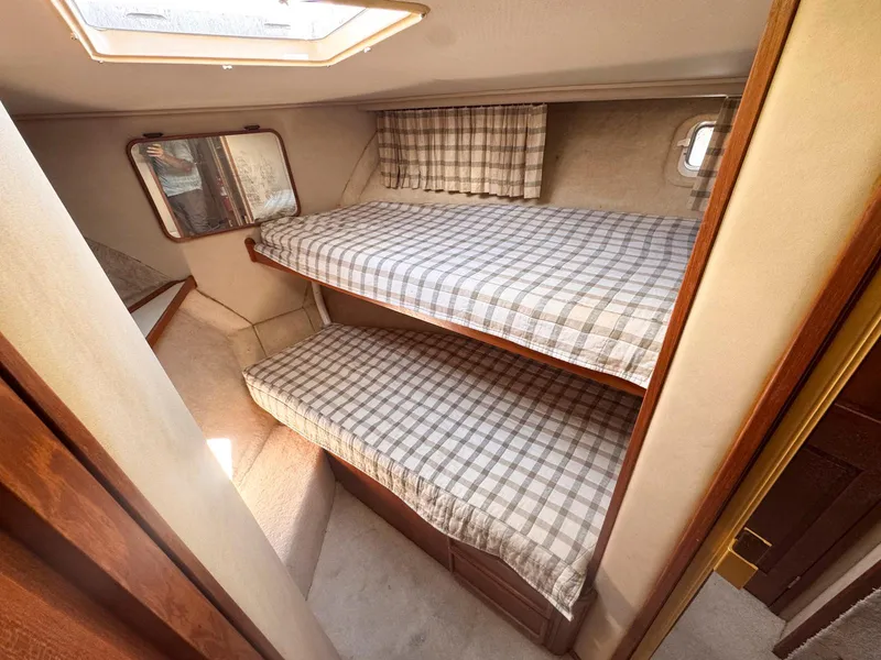 Slide: The Image of 1988 Chris-Craft 501 Motor Yacht cabin with bunk beds and plaid bedding. - 27