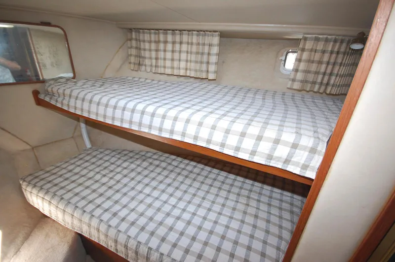 Slide: The Image of 1988 Chris-Craft 501 Motor Yacht cabin with plaid bunk beds and small window. - 28
