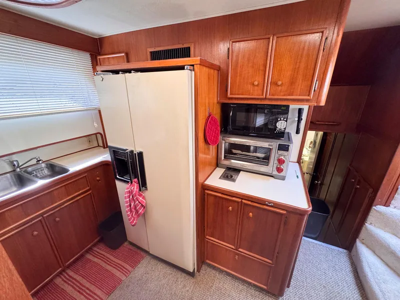 Slide: The Image of 1988 Chris-Craft 501 Motor Yacht kitchen with wood cabinetry, appliances, and dual sink. - 34