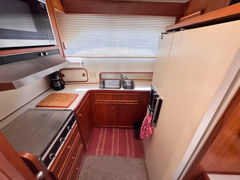 Slide: The Image of 1988 Chris-Craft 501 Motor Yacht kitchen with stove, sink, and wooden cabinetry. - 35