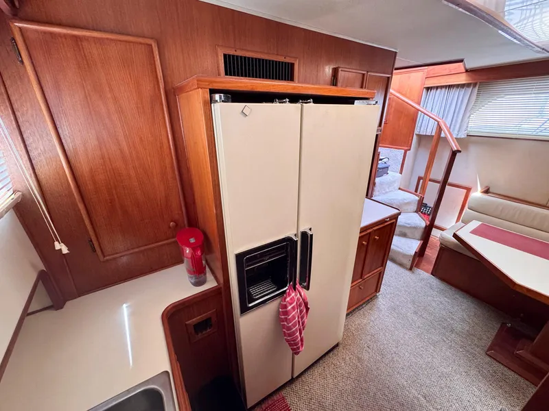 Slide: The Image of 1988 Chris-Craft 501 Motor Yacht interior with kitchen, fridge, and seating area. - 38