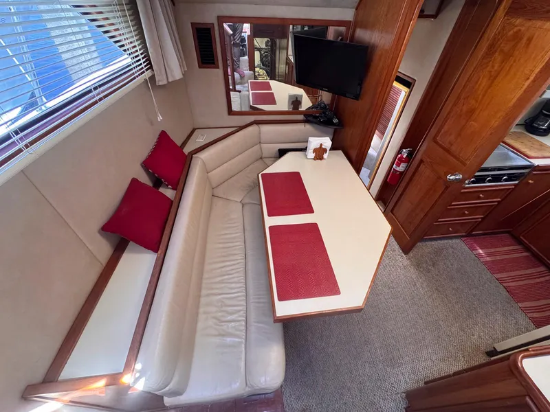 Slide: The Image of 1988 Chris-Craft 501 Motor Yacht interior with dining area, red accents, and wood finishes. - 40