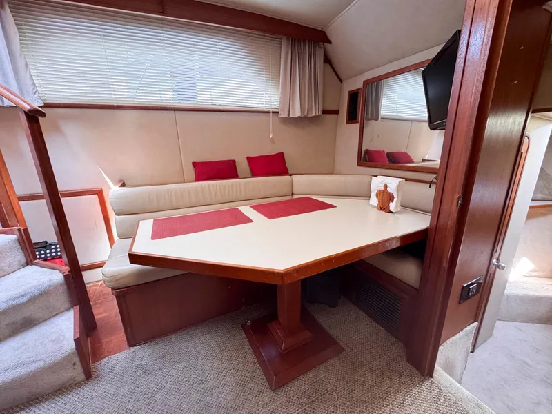 Slide: The Image of 1988 Chris-Craft 501 Motor Yacht interior with dining area, cushioned seating, and wooden table. - 41