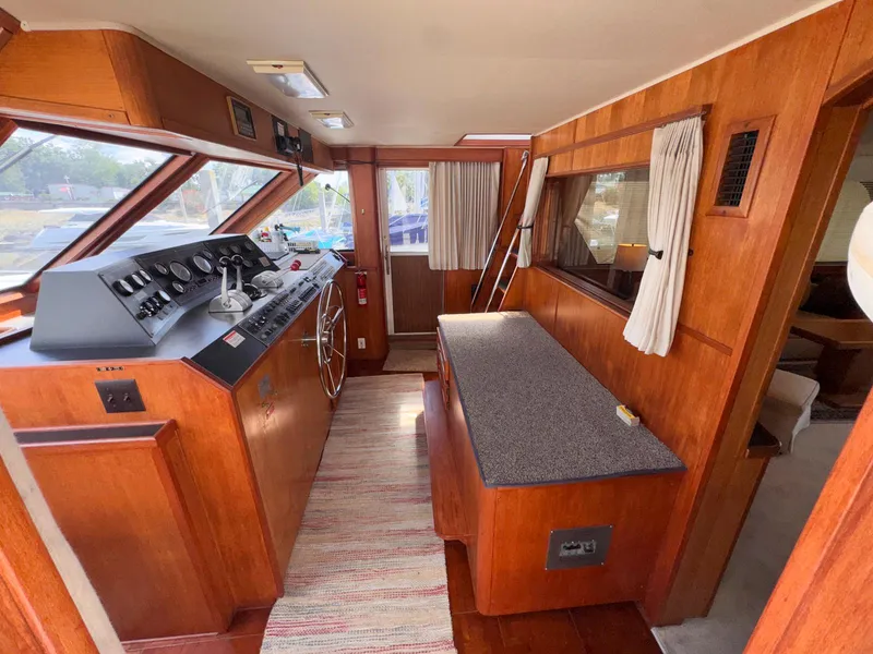 Slide: The Image of 1988 Chris-Craft 501 Motor Yacht interior with helm, wood paneling, and seating area. - 43
