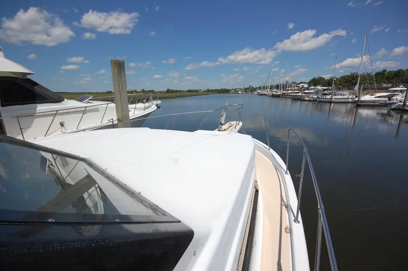 Slide: The Image of 1988 Chris-Craft 501 Motor Yacht docked in a serene marina under a clear blue sky. - 5
