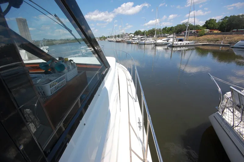 Slide: The Image of 1988 Chris-Craft 501 Motor Yacht docked in a serene marina under a blue sky. - 8