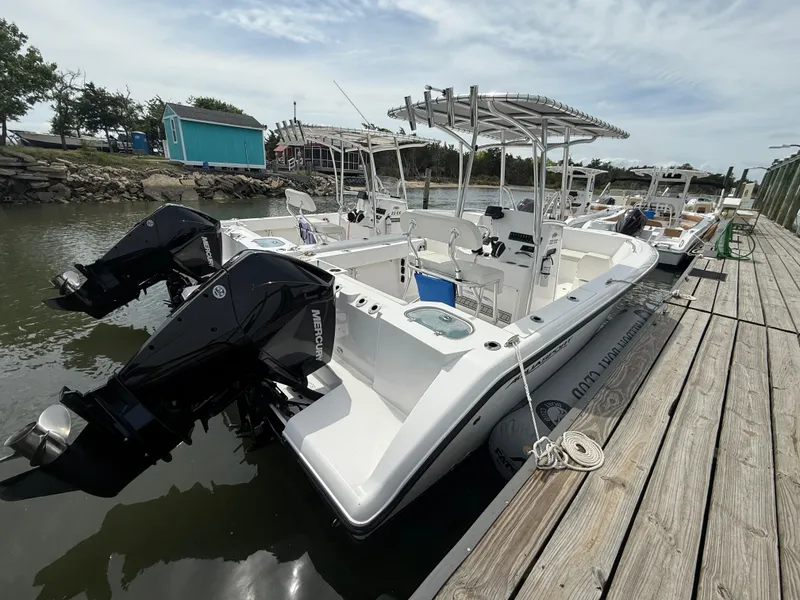 Slide: The Image of 2024 Aquasport 2200 Center Console boat docked with dual outboard motors. - 4