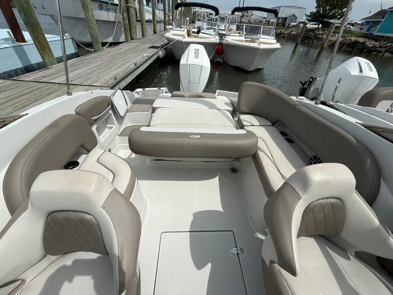 Slide: The Image of 2023 Crownline Eclipse E235 XS boat interior with beige seating at a marina. - 8