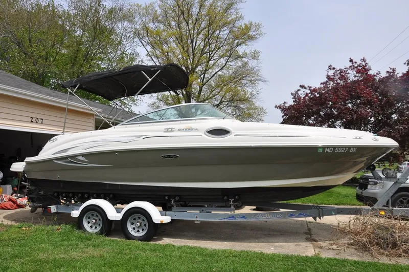 Slide: The Image of 2006 Sea Ray 240 Sundeck boat on trailer, parked in driveway, surrounded by trees. - 0