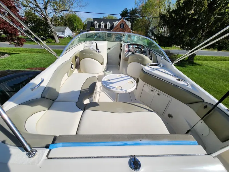 Slide: The Image of 2006 Sea Ray 240 Sundeck boat with spacious seating and table, parked outdoors. - 10