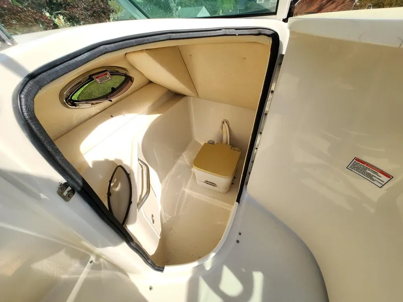 Slide: The Image of 2006 Sea Ray 240 Sundeck interior cabin with compact toilet and small window. - 15