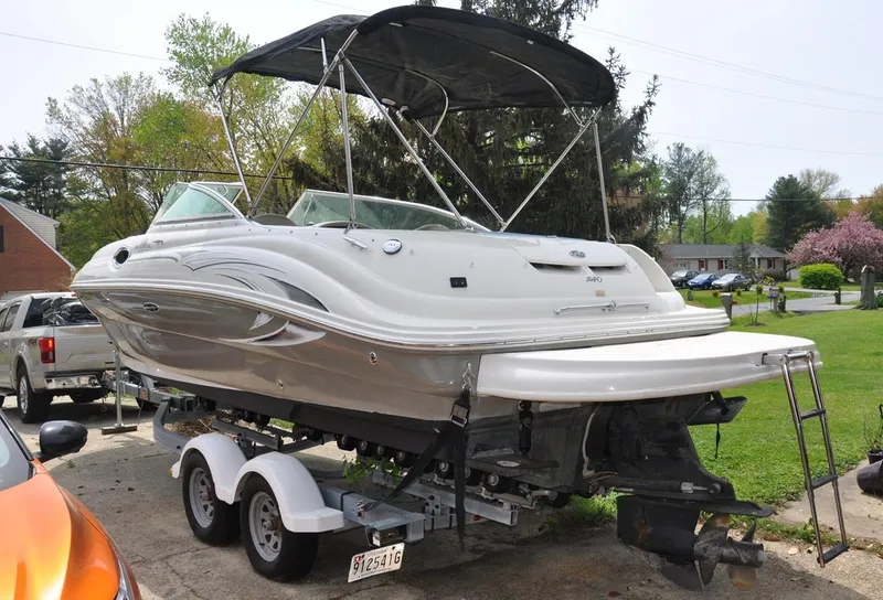 Slide: The Image of 2006 Sea Ray 240 Sundeck boat on trailer, parked outdoors with trees in background. - 3